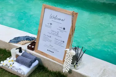a sign next to a swimming pool with towels and a menu at Villa Alice by Villa Finder in Seminyak