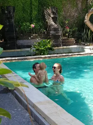 two people and a baby in a swimming pool at Puri Mesari Hotel in Sanur
