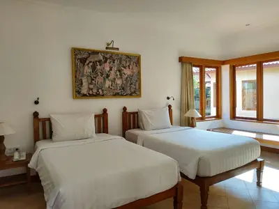 a bedroom with two beds and a painting on the wall at Puri Mesari Hotel in Sanur