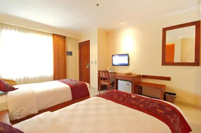 a hotel room with two beds and a desk and a mirror at Restu Bali Hotel in Legian