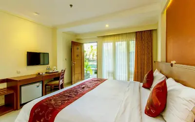 a hotel room with a bed and a desk and a television at Restu Bali Hotel in Legian