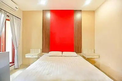 a bedroom with a large bed with a red wall at KoolKost near Sunset Road Seminyak - Minimum Stay 30 Nights in Seminyak
