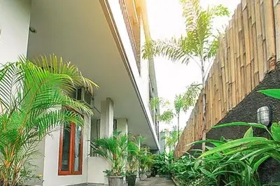 a building with a courtyard with palm trees and plants at KoolKost near Sunset Road Seminyak - Minimum Stay 30 Nights in Seminyak