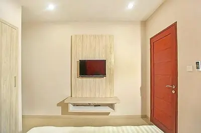 a living room with a tv and a red door at KoolKost near Sunset Road Seminyak - Minimum Stay 30 Nights in Seminyak