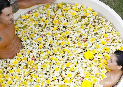 a man and a woman in a bath tub filled with flowers at eqUILIBRIA Seminyak in Seminyak