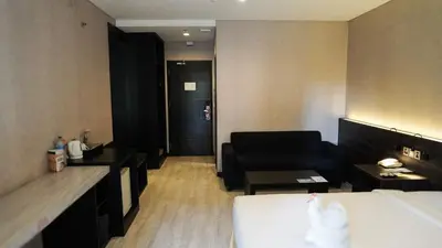 a hotel room with a bed and a couch at Grand Kuta Hotel and Residence in Legian