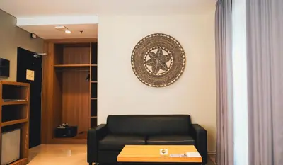 a living room with a couch and a clock on the wall at Grand Kuta Hotel and Residence in Legian