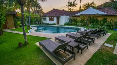 an overhead view of a pool with benches and an umbrella at Bali Dyana Villas in Seminyak