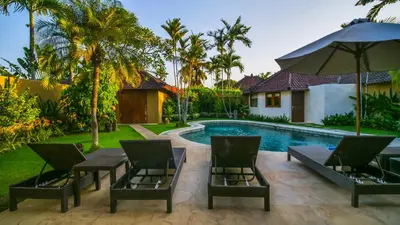 a patio with chairs and an umbrella next to a pool at Bali Dyana Villas in Seminyak