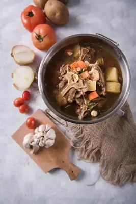 a pot of soup with vegetables and meat on a table at The Banyumas Villa in Denpasar