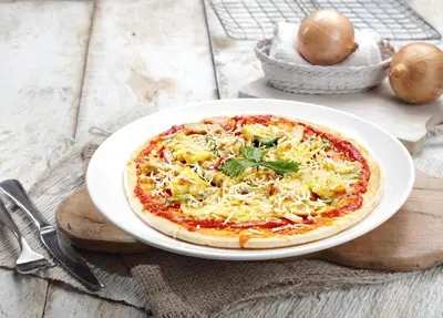 a pizza on a white plate on a table at The Banyumas Villa in Denpasar