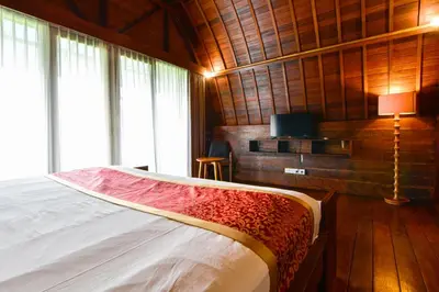 a bedroom with a bed in a room with wooden walls at The Lumbung Wood Villa in Seminyak