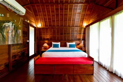 a bedroom with a large bed with a red bench at The Lumbung Wood Villa in Seminyak