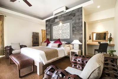 a bedroom with a bed and two chairs at Sunset Paradise at Temple Hill Jimbaran in Jimbaran
