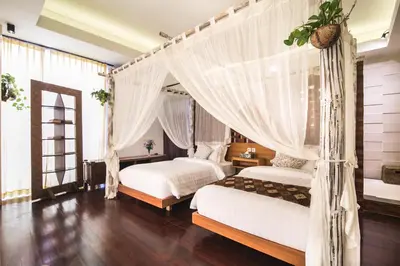two beds in a room with white curtains at Sunset Paradise at Temple Hill Jimbaran in Jimbaran
