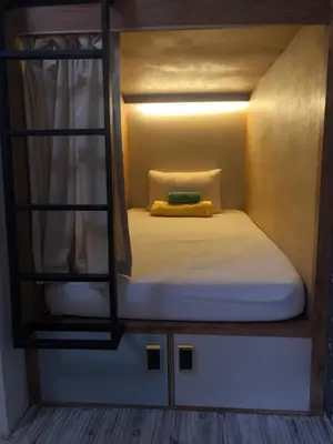 a small room with a bed with a yellow pillow at Stellar Capsules in Seminyak