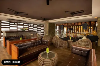 a lobby with leather couches and tables and a stage at Grand Ixora Kuta Resort in Kuta