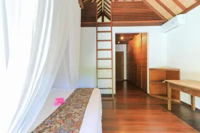 a bedroom with a bed with a ladder and a desk at Villas Sin Sin in Canggu