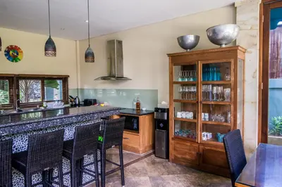 a kitchen with a counter and a bar with chairs at Bali Mystique Hotel & Apartment in Seminyak