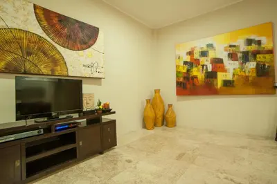 a living room with a flat screen tv and a painting at Bali Mystique Hotel & Apartment in Seminyak