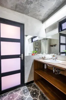 a bathroom with a sink and a large door at Balissimo Suites Seminyak by Betterplace in Seminyak