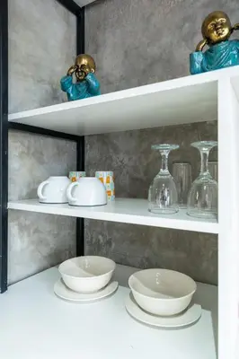 a shelf with plates and bowls on it at Balissimo Suites Seminyak by Betterplace in Seminyak