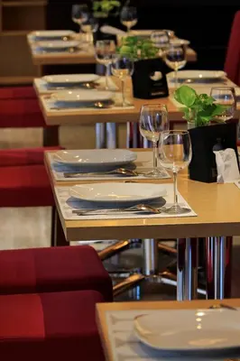 a table with plates and wine glasses on it at Ohana Hotel Kuta in Kuta