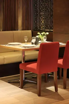 a dining room table with two red chairs and a table at Ohana Hotel Kuta in Kuta