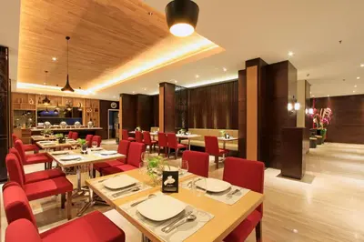a restaurant with wooden tables and red chairs at Ohana Hotel Kuta in Kuta