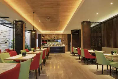 a restaurant with tables and chairs and a bar at Ohana Hotel Kuta in Kuta