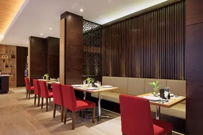 a dining room with tables and red chairs at Ohana Hotel Kuta in Kuta
