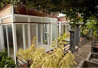 a house with glass doors and plants in front of it at Aqua Bali Villa in Canggu