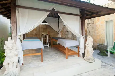 a patio with a bed and a table and chairs at Bali Court Hotel & Apartment in Legian