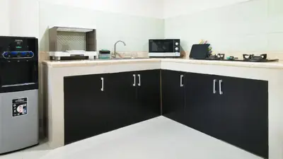a kitchen with black cabinets and a sink and a refrigerator at Kumpul Kumpul Villa Seminyak - CHSE Certified in Seminyak