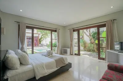 a bedroom with a large bed and sliding glass doors at Villa Harmony - Residence in Seminyak