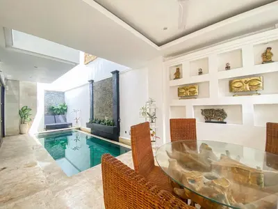 a dining room with a glass table and a swimming pool at Villa Harmony - Residence in Seminyak