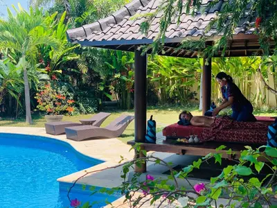 a woman sitting on a bed next to a pool at Casa Priya Seminyak in Kerobokan