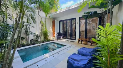 a swimming pool in a garden with palm trees at Villa Bugis Kayu Aya Seminyak in Seminyak