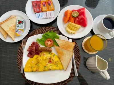 a table with plates of breakfast foods and a cup of coffee at Villa Bugis Kayu Aya Seminyak in Seminyak