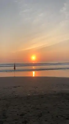 a sunset on the beach with an umbrella at Villa Jalun in Seminyak