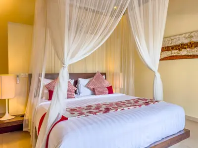 a bedroom with a large white bed with curtains at Villa Bugis Drupadi Seminyak in Seminyak