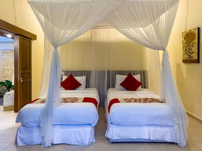 two beds in a bedroom with white curtains and red pillows at Villa Bugis Drupadi Seminyak in Seminyak