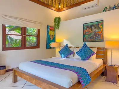 a bedroom with a large bed with blue pillows at Villa Bugis Drupadi Seminyak in Seminyak