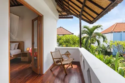 a room with a balcony with a chair at Unicorn Shelter Villa in Seminyak