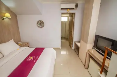 a hotel room with a bed and a flat screen tv at Abian Biu Mansion in Canggu