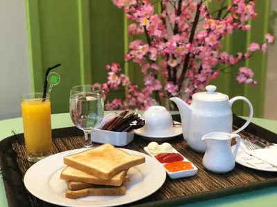 a table with a plate of toast and orange juice at Ibis Styles Bali Denpasar in Denpasar