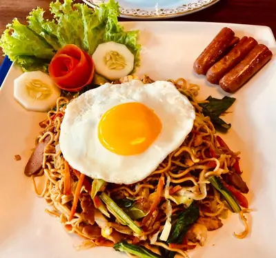 a plate of food with an egg on top of noodles at Villa Essence in Seminyak