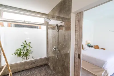 a bathroom with a shower and a bed and a window at Villa Opaline by Alfred in Bali in Seminyak