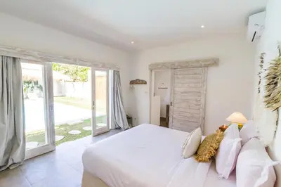 a bedroom with a large white bed and large windows at Villa Opaline by Alfred in Bali in Seminyak