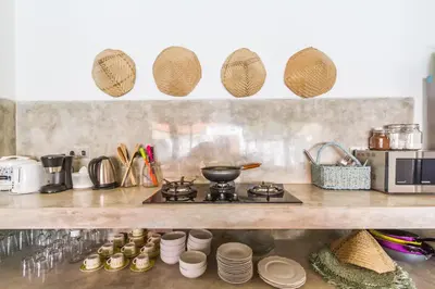 a kitchen with a stove and plates on a shelf at Villa Opaline by Alfred in Bali in Seminyak